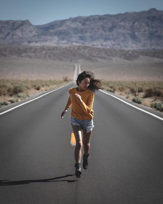 girl running on the road in the middle of desert