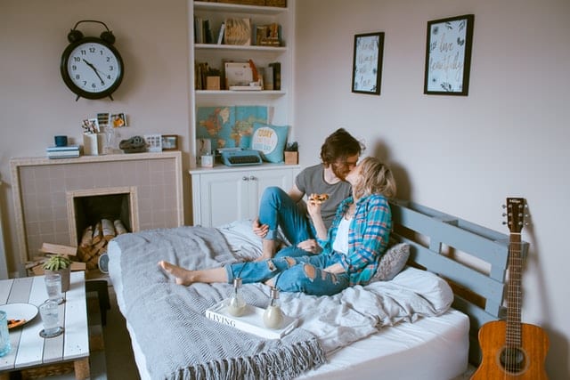 image showing two young adults kissing in bed