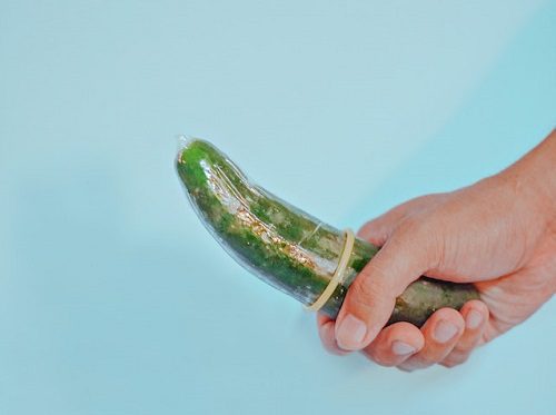 Person holding a cucumber in a condom