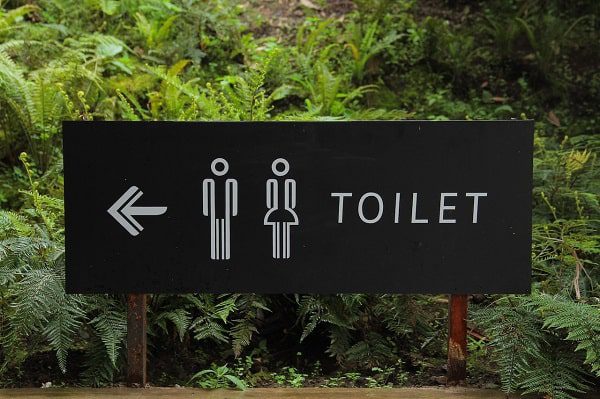 Toilet sign with plants in the background