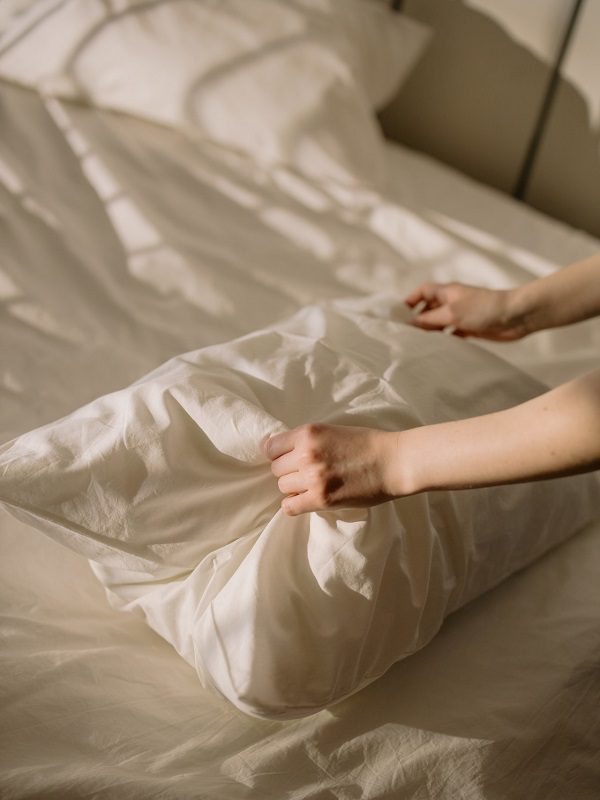 Placing a pillow on a bed